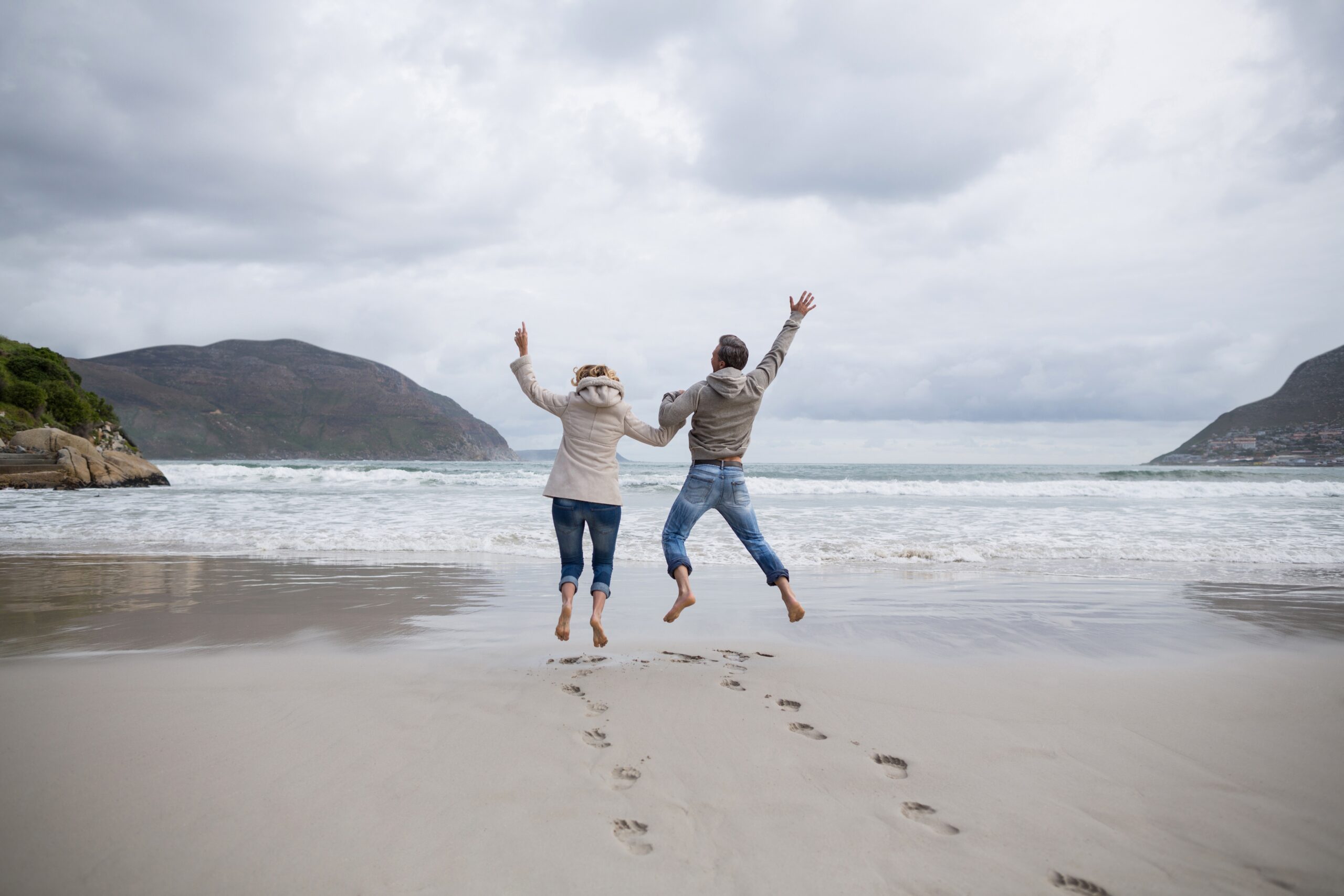 Mature couple jumping in the air on a beach